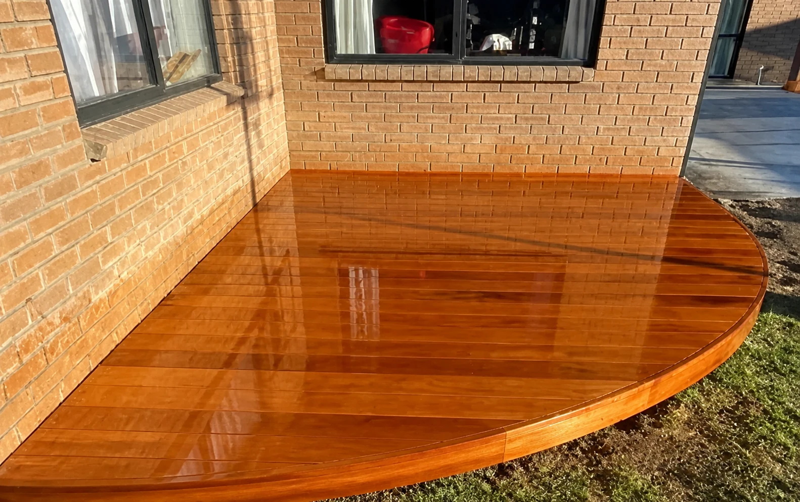 Curved timber entertaining deck built against a brick home